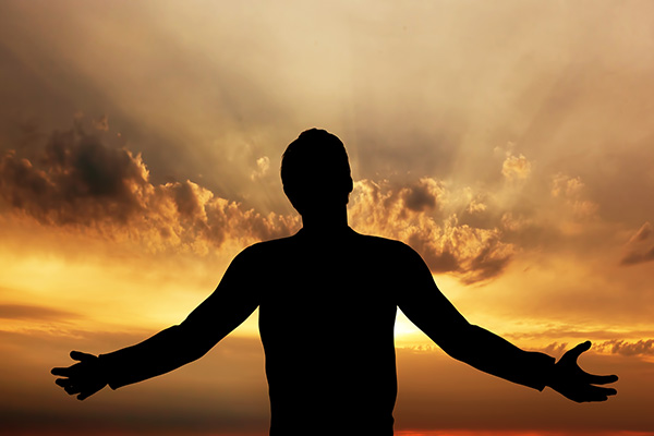 Man with arms outstretched looking at sunrise